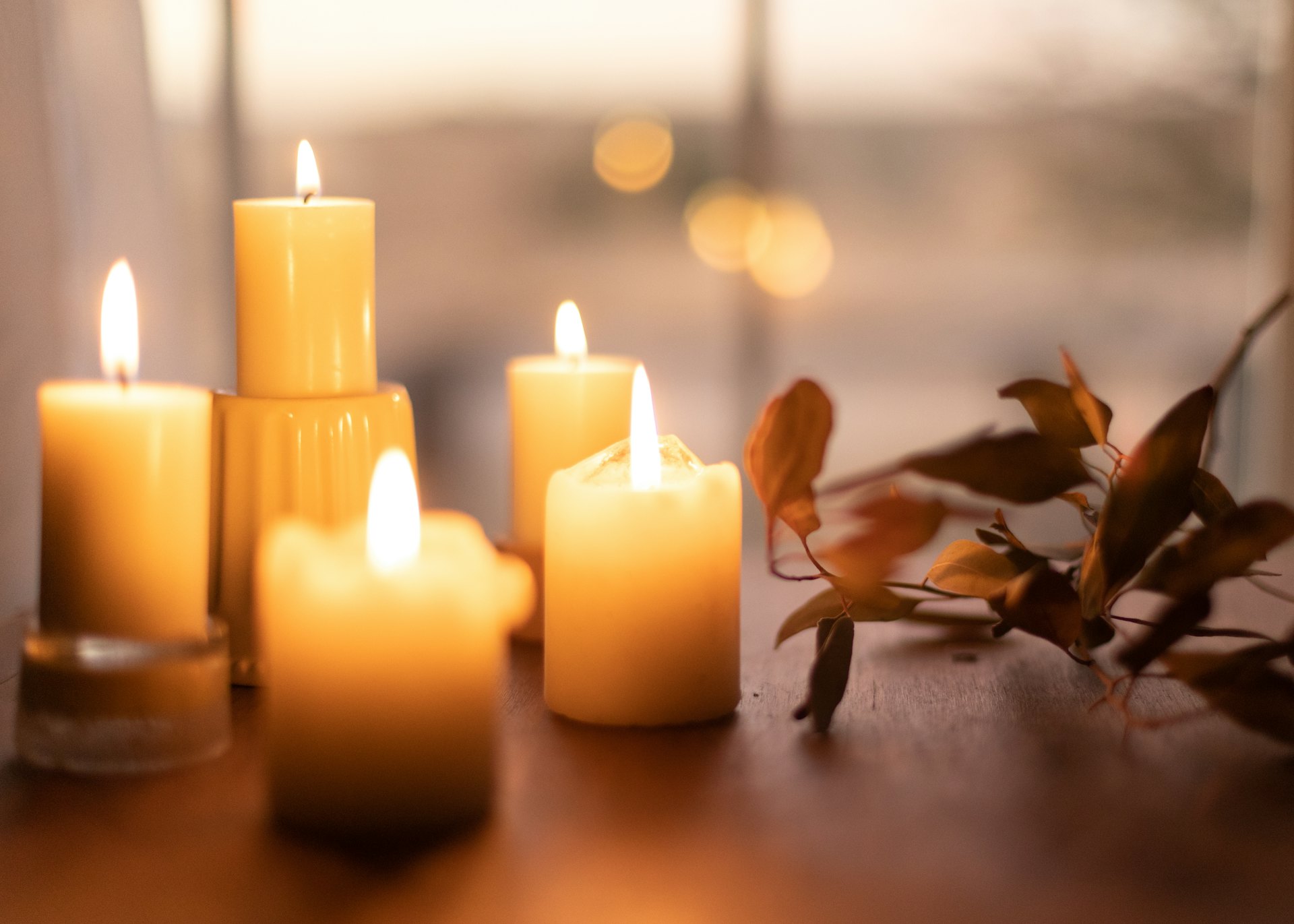 Lit white pillar candles on a wooden table